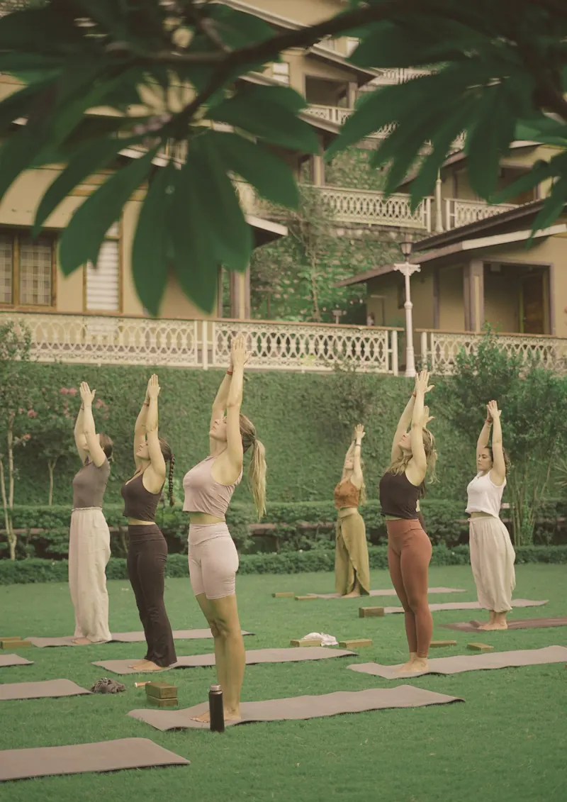 Women practicing yoga together on a sun-drenched resort lawn — movement, stillness, and the quiet luxury of time for yourself
